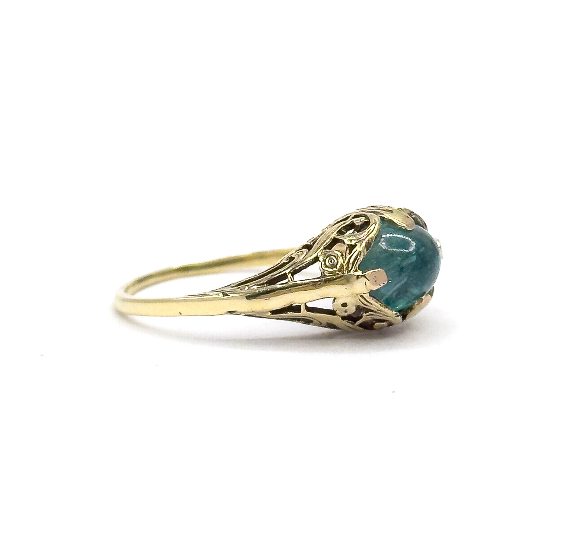 Direct eye-level profile of the ring against white, the cabochon seen edge-on in its prongs so the domed top and the airy pierced sidewall of the gallery stand out above the thin shank.