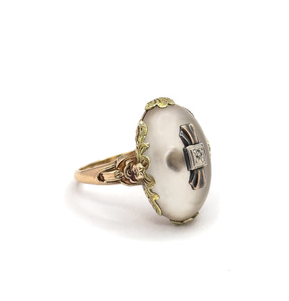 Angled three-quarter view where the cabochon's face turns toward the camera, revealing the small square white metal plaque holding the diamond between two dark tapering bands.