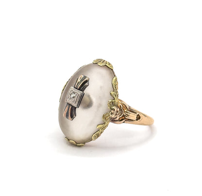 Side-on against white, the oval rock crystal cabochon rising high in its leafy gold gallery, with the sculpted shoulders and tapering shank clearly visible in profile.