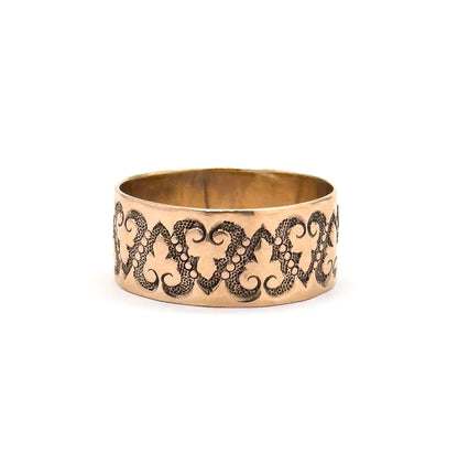 Standing upright with the opening a narrow dark oval at the top, this view shows the plain smooth upper edge of the band above the heart chain, with no lettering in sight.
