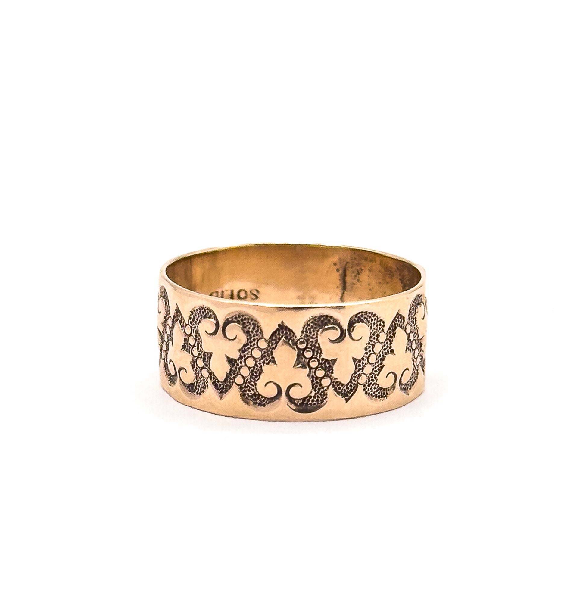 The ring stands upright on a white background, showing the full width of the band, the darkened recesses around the raised hearts, and part of a stamp inside the shank.