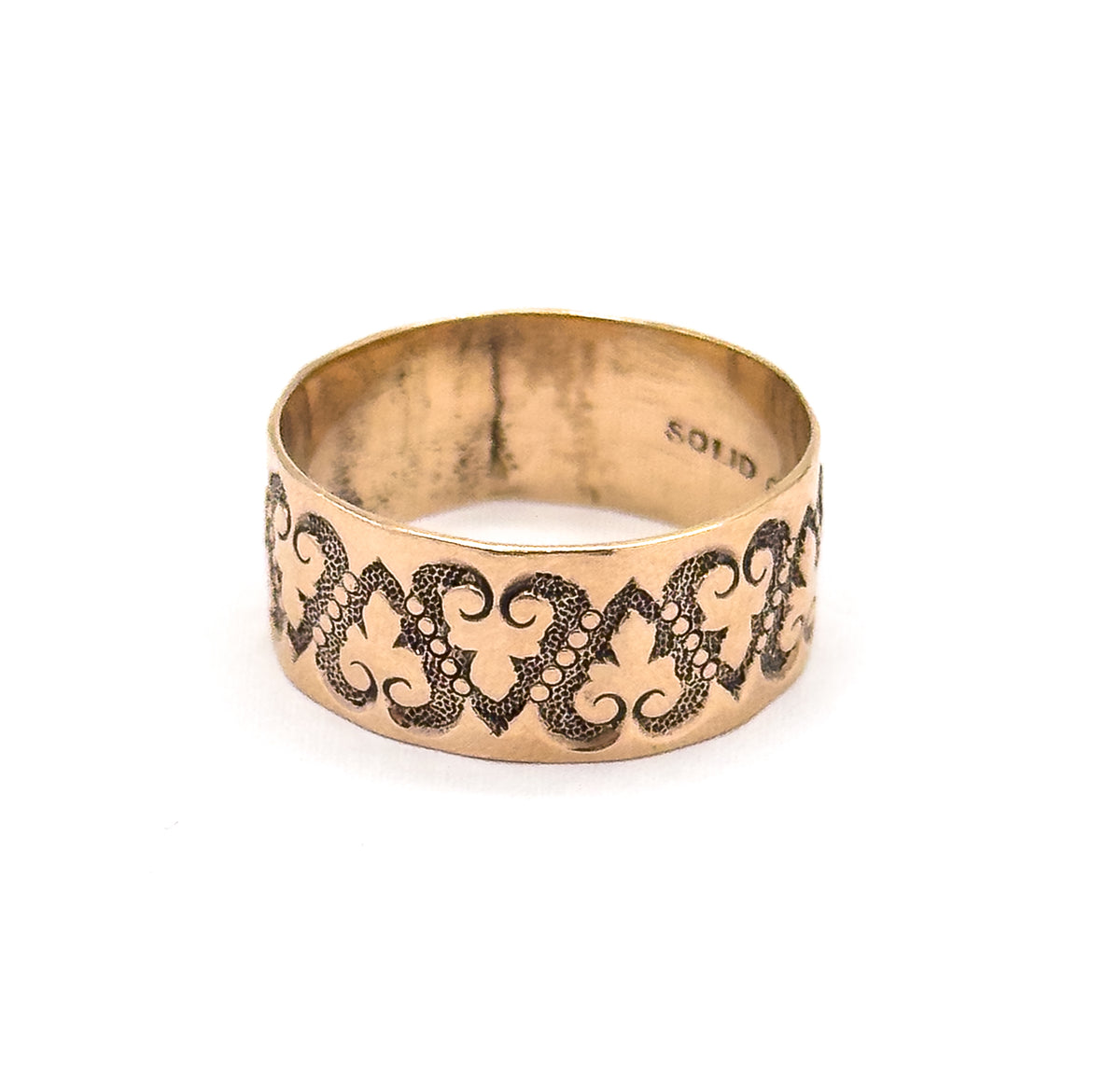 Tipped slightly back so the inner wall curves away, part of the stamped lettering sits along the right side of the shank while the heart chain wraps the lower front of the rose gold band.