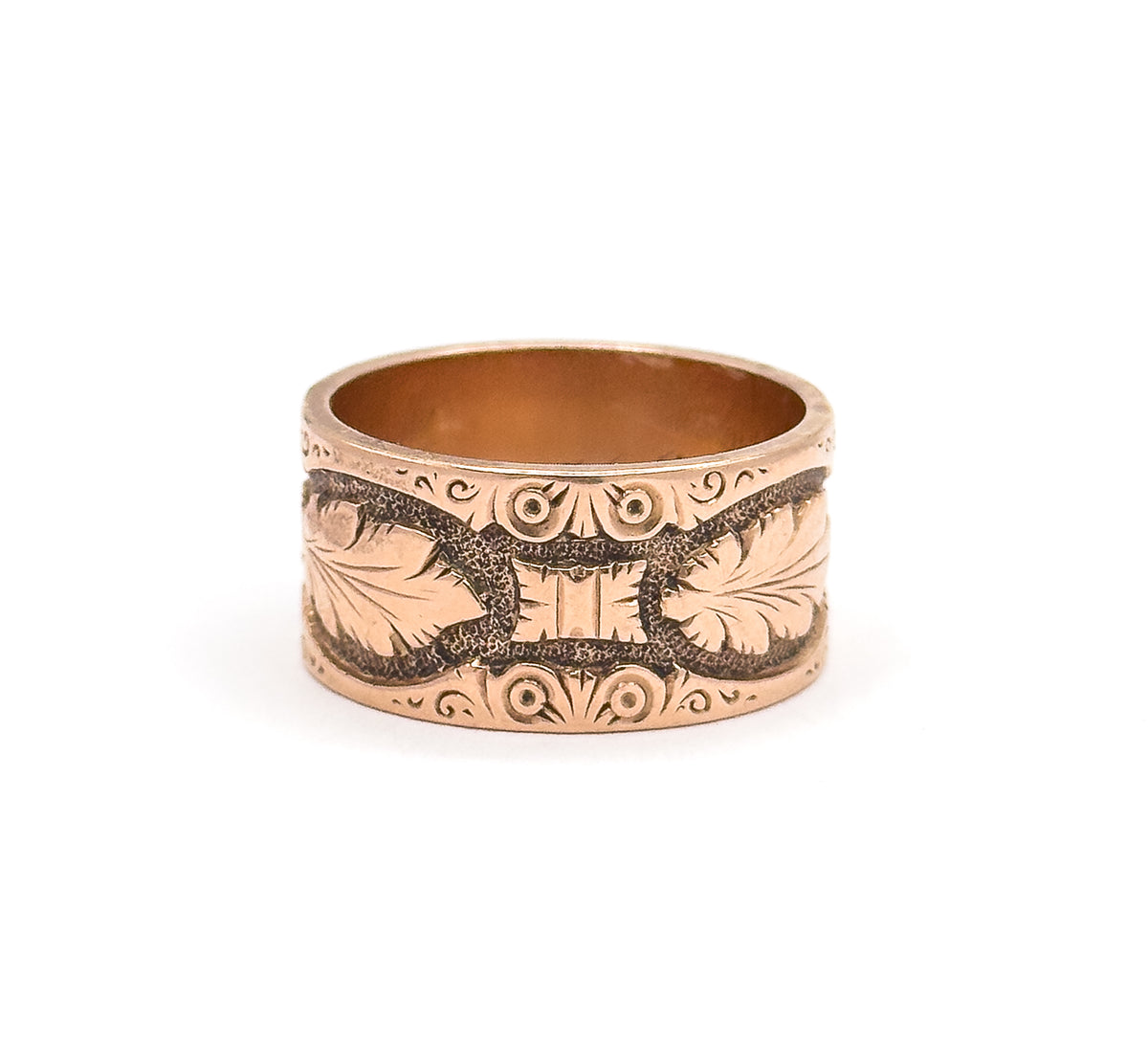 Straight-on from the front, the wide rose gold band stands upright with mirrored leaves meeting at a central motif and dotted scroll borders running along both rims.