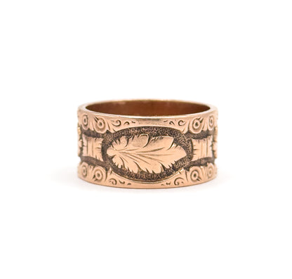 Viewed slightly from above so the smooth inner wall of the shank shows, a single leaf sits inside a stippled oval cartouche at the centre of the band, flanked by scrolls and dotted roundels.