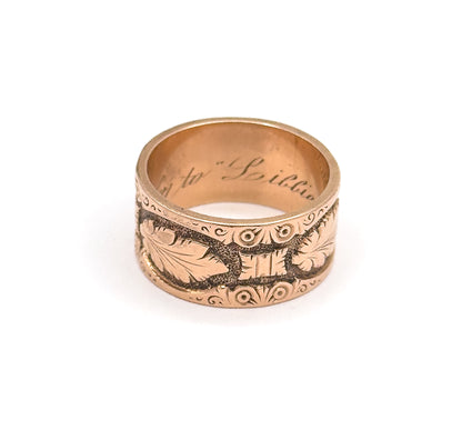 Viewed straight on with the band standing upright, the open shank reveals cursive script curving across the inside back while scrolled borders frame the leaf panels above and below.