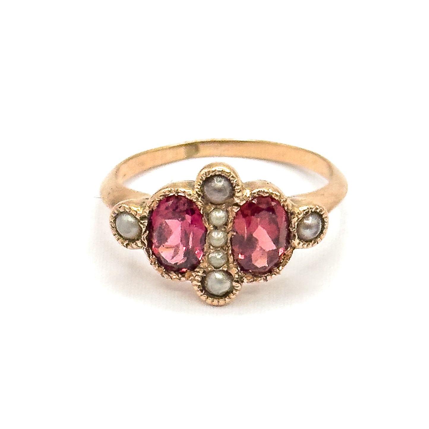 Straight-on from the front, the two oval garnets sit level either side of a vertical row of seed pearls, with a pearl above, below and on each milled shoulder bezel.