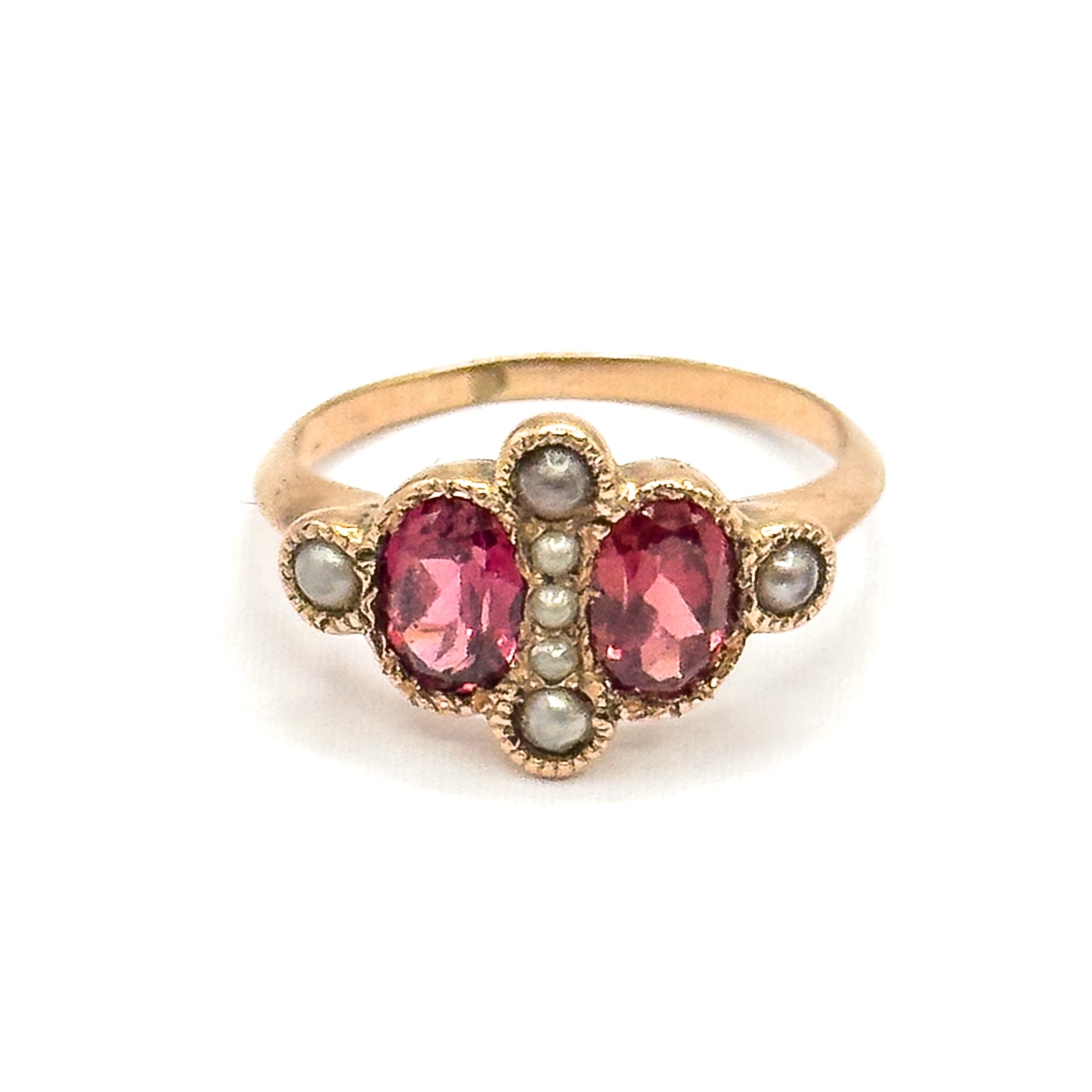 Straight-on from the front, the two oval garnets sit level either side of a vertical row of seed pearls, with a pearl above, below and on each milled shoulder bezel.