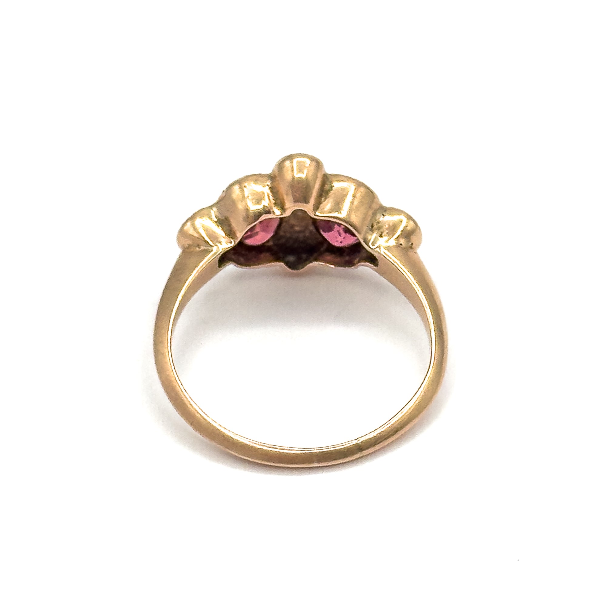 Viewed from behind against white, the open rose gold gallery and the underside of the setting show, with the garnets glimpsed pink between the scalloped rows of seed pearls.