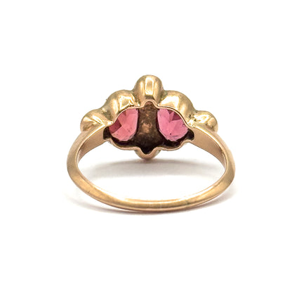 From directly behind, the scalloped rose gold backs of the pearl settings and the garnets showing pink through the open bezel sit above the full circle of the slender shank.