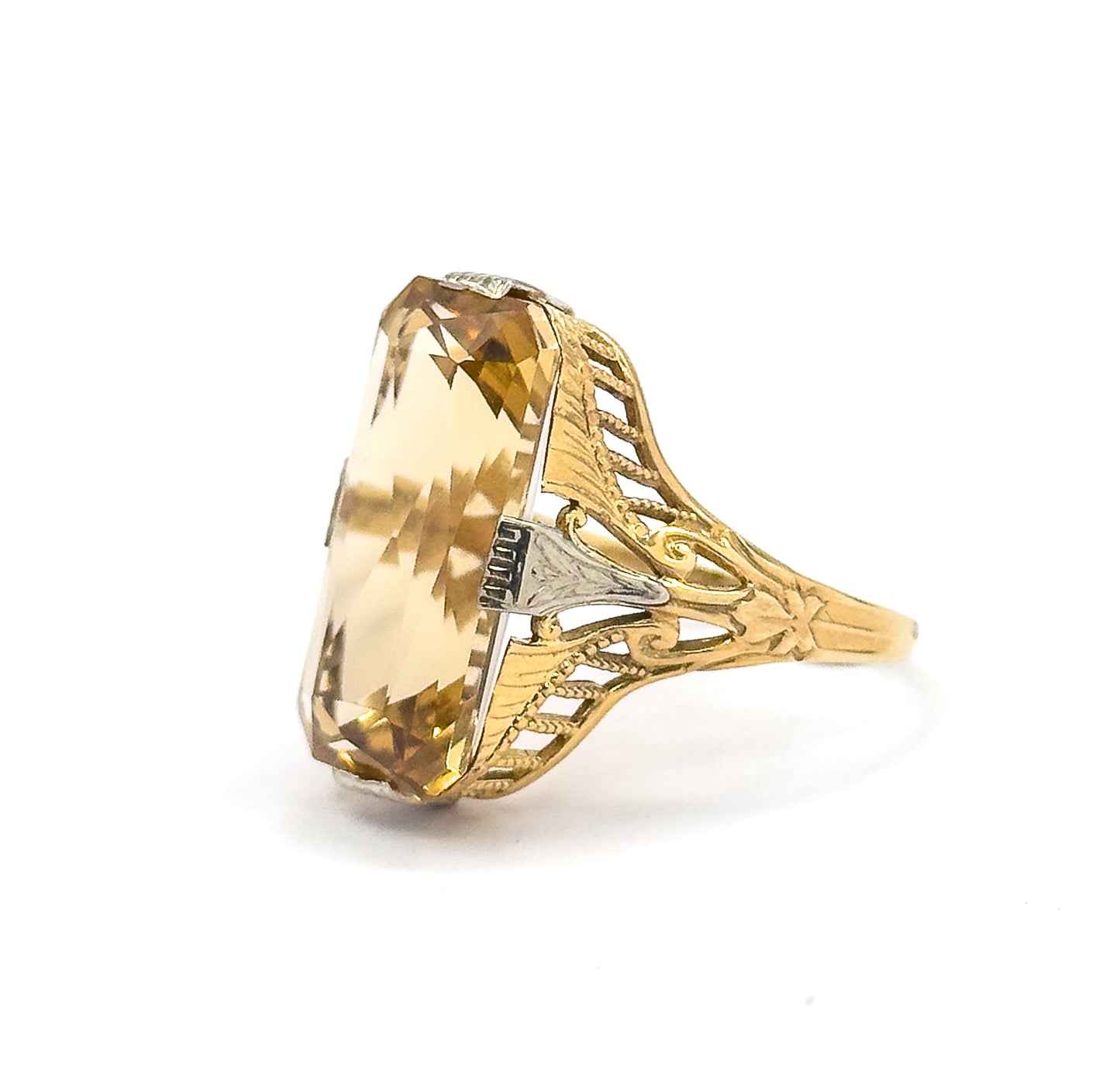 Profile view from the stone's long edge, showing how tall the setting stands above the slim tapering band, with the pierced scrollwork shoulder and one white gold prong in full silhouette.