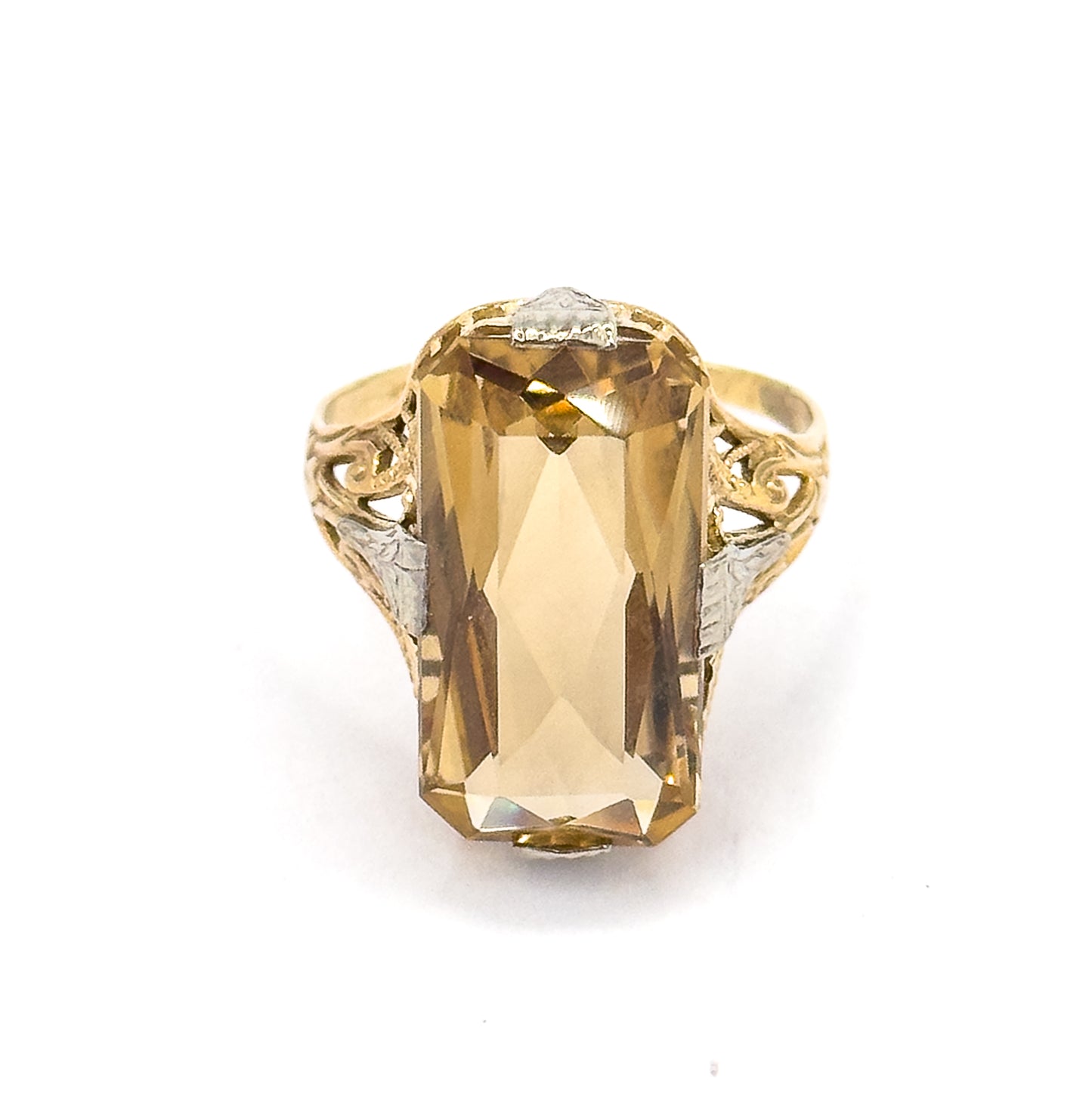 Straight-on view from directly above, the elongated rectangular citrine filling the setting face-up with white gold prongs at top and bottom and scrolled yellow gold filigree shoulders each side.