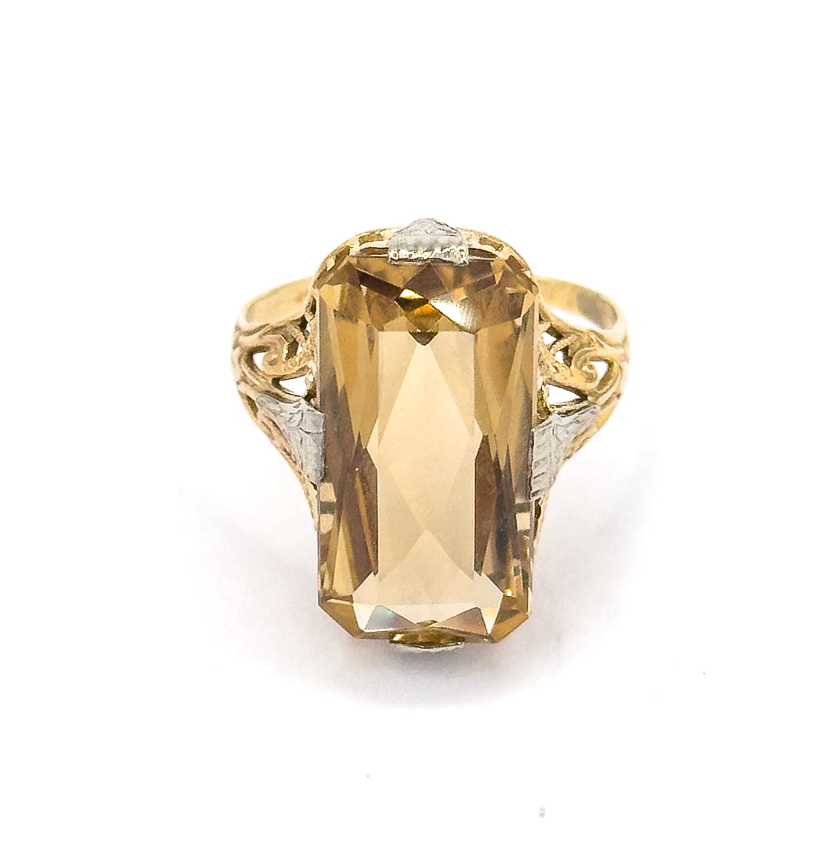 Straight-on view from directly above, the elongated rectangular citrine filling the setting face-up with white gold prongs at top and bottom and scrolled yellow gold filigree shoulders each side.