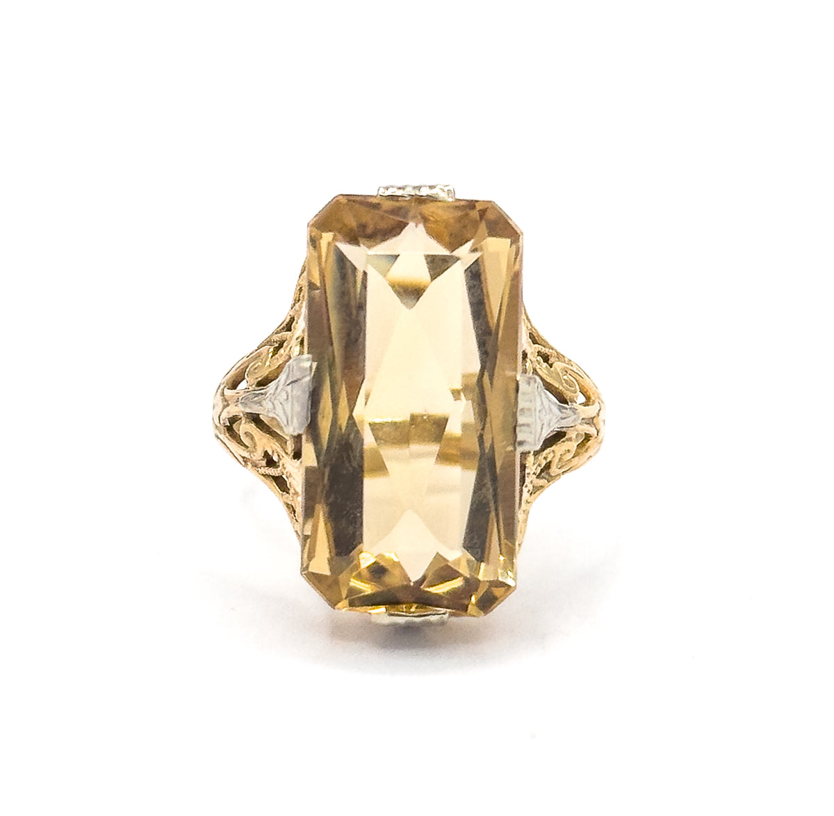 Tightly cropped face-up close-up filling the frame, the citrine's stepped internal facets and pale orange-yellow glow catching the light between the milgrained white gold prongs.