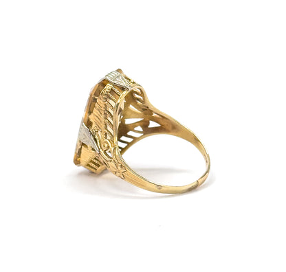Profile view off the hand against plain white, showing the setting's height above the slim shank and the pierced arcaded gallery supporting the citrine from the side.