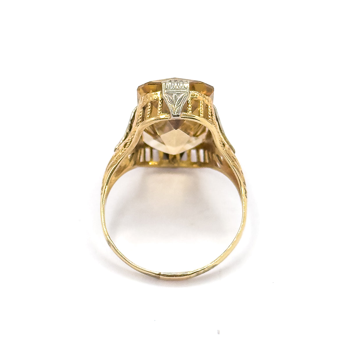 End-on view looking straight through the shank's open circle, so the underside of the citrine, the arcaded gallery bars and one white gold prong are seen from beneath.