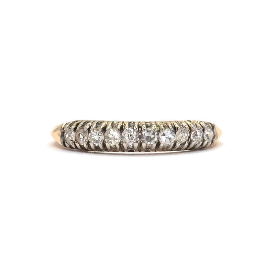 Level side-on view against white showing the full row of ten round diamonds sitting in a shallow arc, ridged prongs between them, the yellow gold shank tapering away at each shoulder.