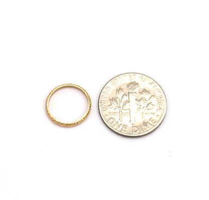 The ring lies flat beside a dime, its slender chased band barely over half the coin's width, giving a clear sense of scale.