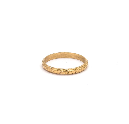 Set small within a wide white frame that conveys how tiny the ring is, the band tilts just enough to show the chased front edge and the plain inner wall behind it.