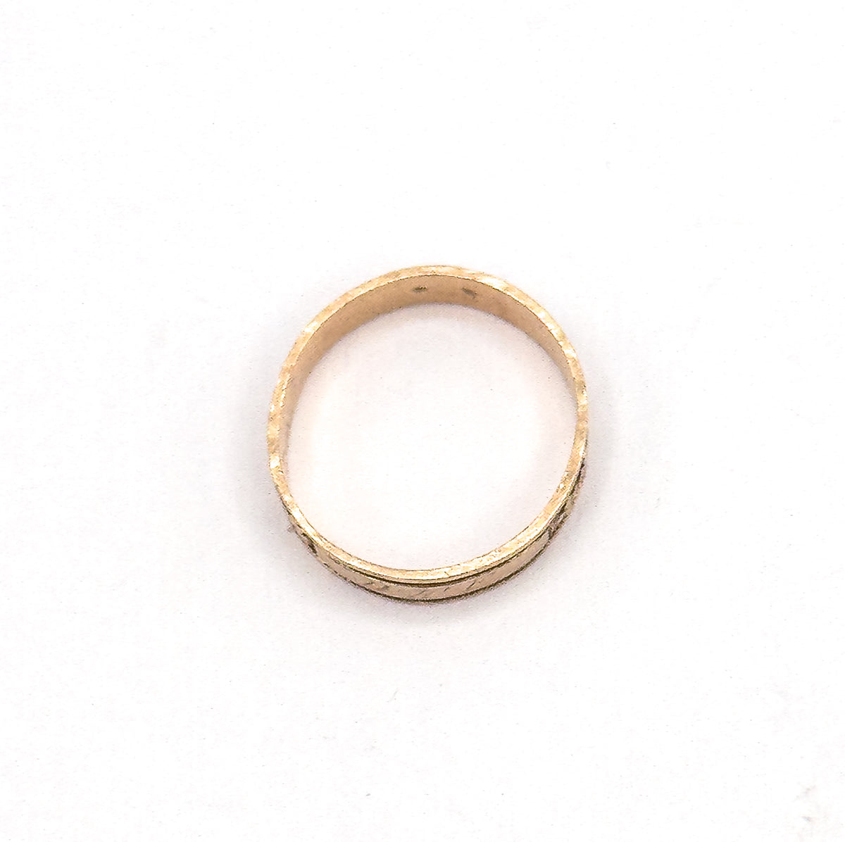 The hoop lies flat against white, seen through the open circle so the inner shank and the narrow outer edge of the clover-engraved band are both visible.