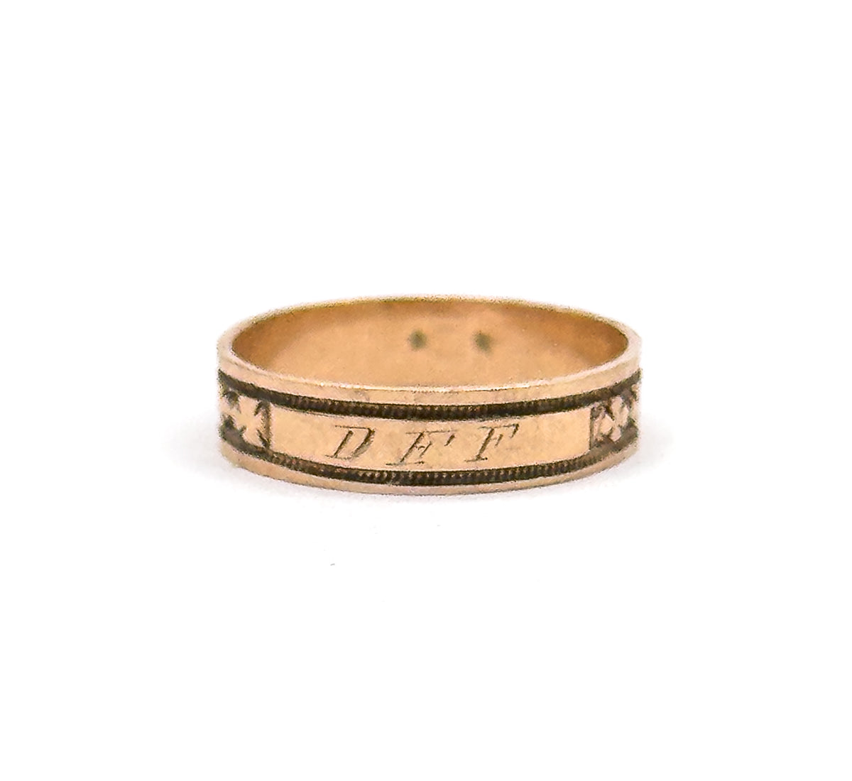 The band stands upright against white with the engraved initials "DFF" in the cartouche facing the camera, a clover motif at each side and the smooth inner shank visible above.