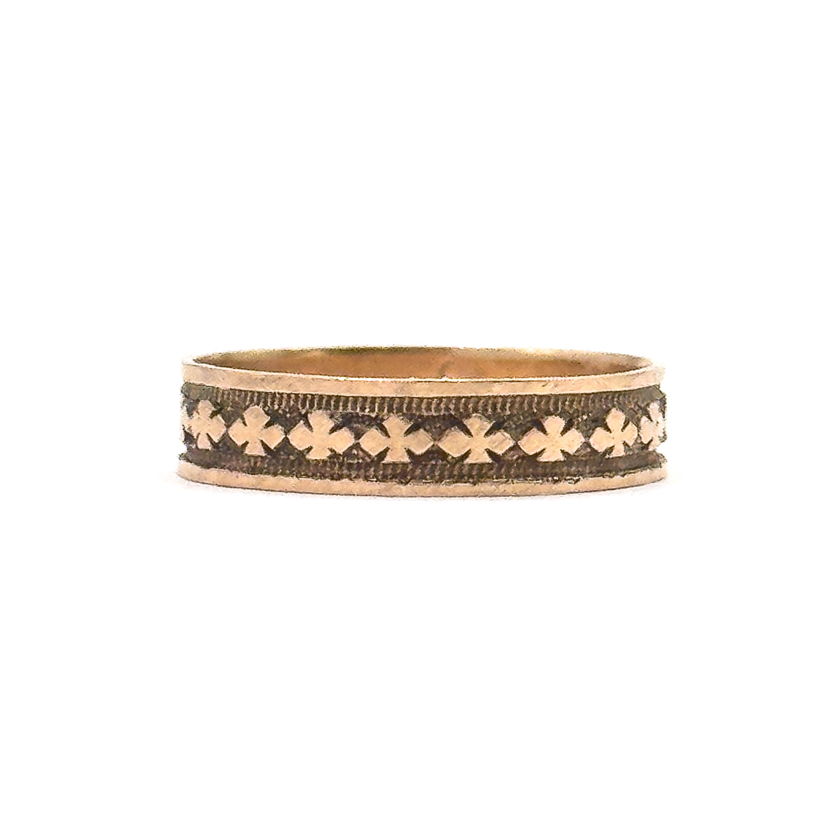 Straight-on side view filling the frame with the unbroken row of clover motifs, the dark patina sitting in the recesses between them and the plain rims above and below catching the light.