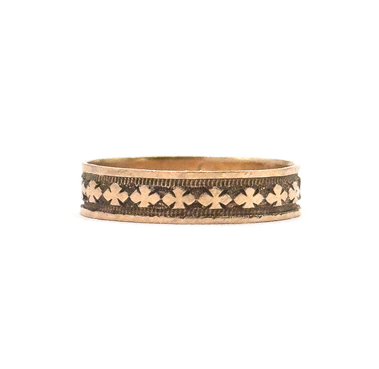 Straight-on side view filling the frame with the unbroken row of clover motifs, the dark patina sitting in the recesses between them and the plain rims above and below catching the light.