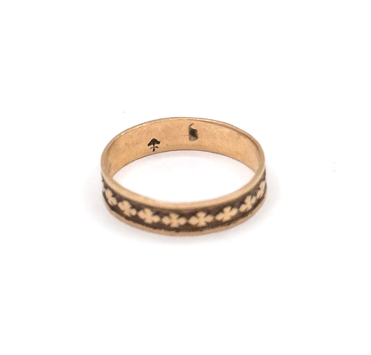 Tilted to show the inside of the shank, where the small anchor stamp and a second tiny mark sit on the smooth rose gold above the clover-patterned outer edge.