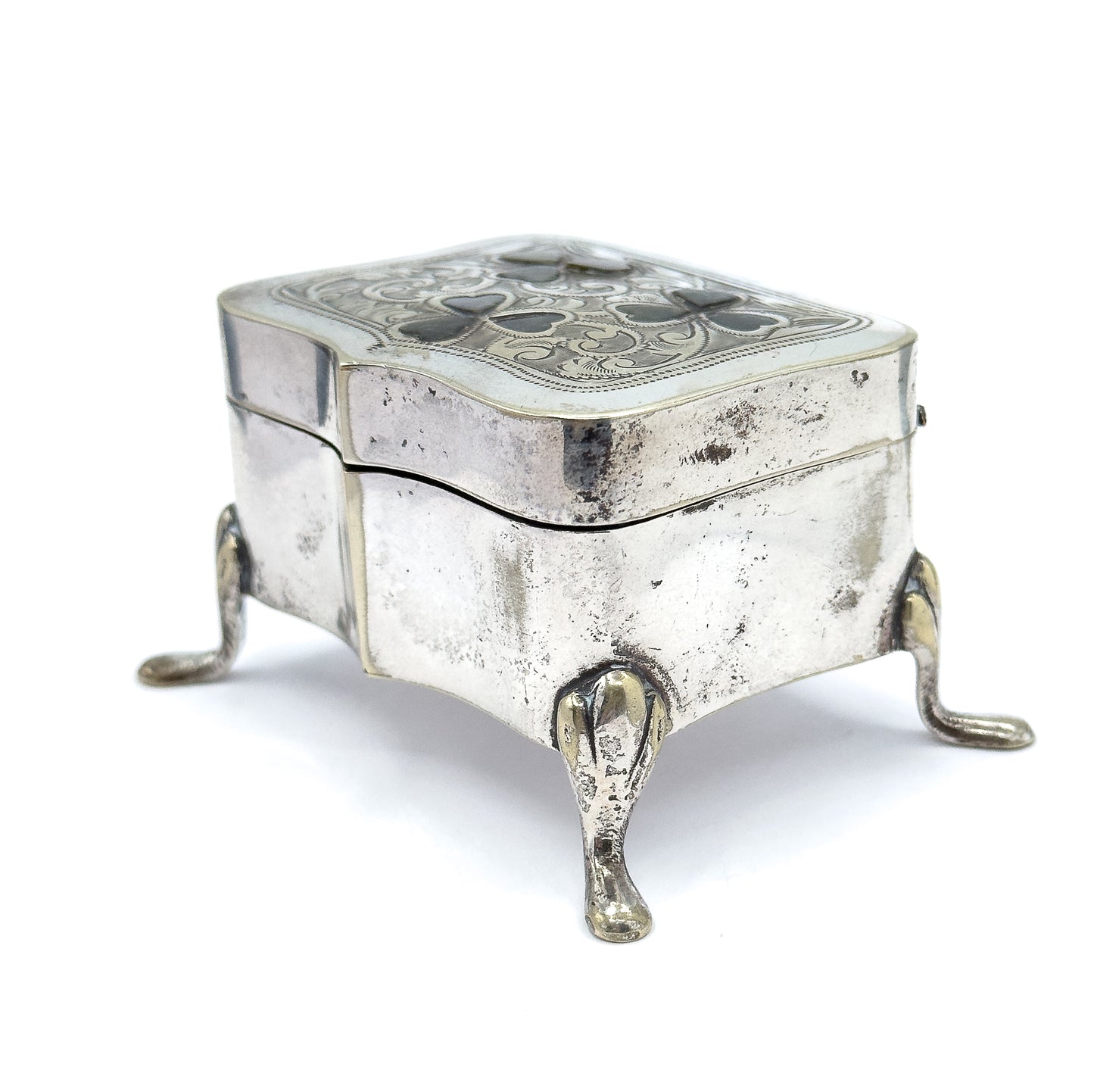 High three-quarter view from above, looking down onto the full engraved lid with its three green marble clovers, the serpentine body below and three teardrop feet splaying outward.