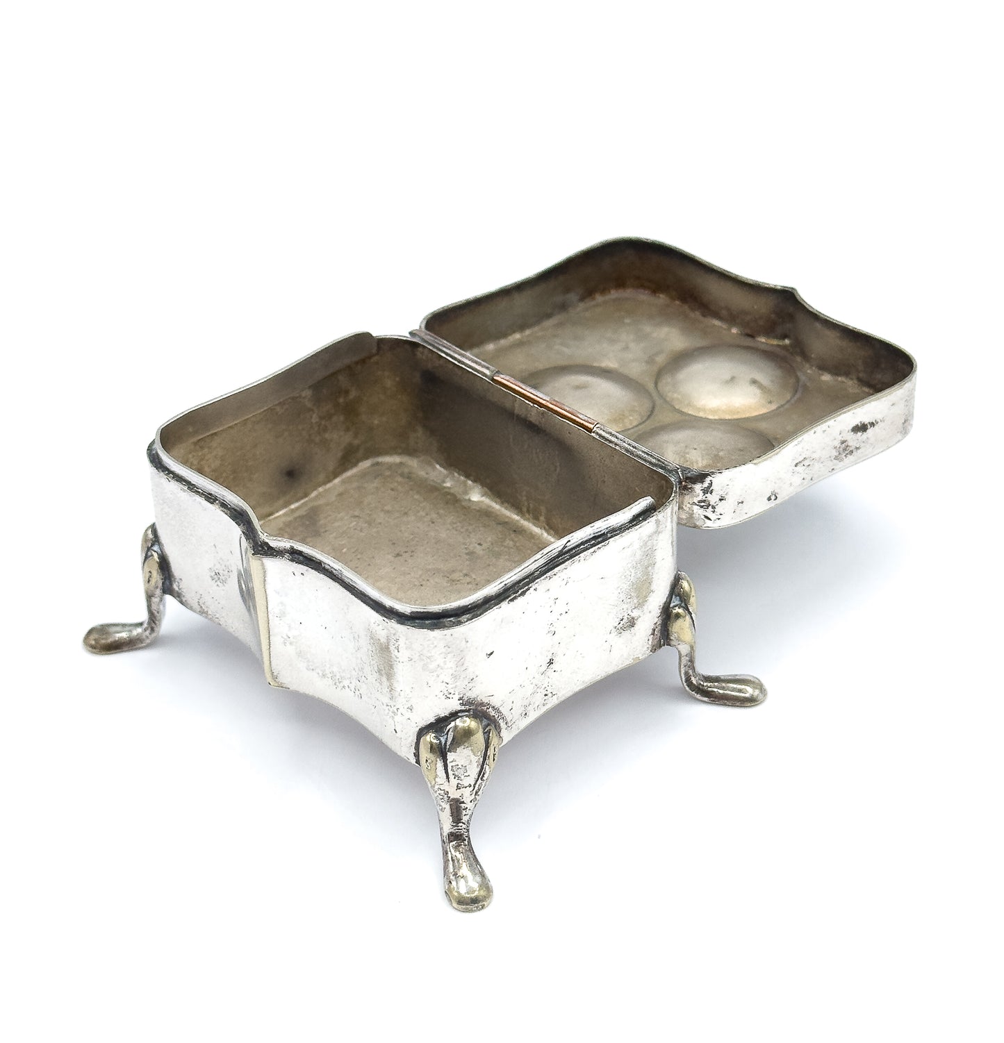 The box open on its hinge, showing the empty shaped interior of the body and the plain inside of the lid, with three curved feet supporting it.