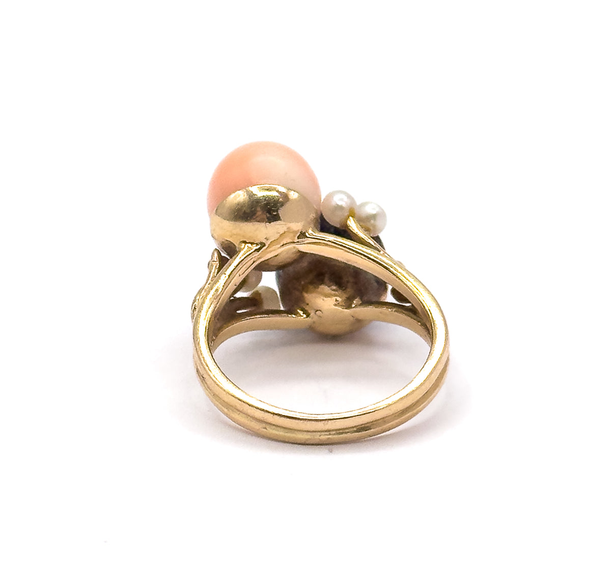 Almost the same view with slightly different angle, showing the twin bands of the split shank meeting the open gallery and the gold cup cradling the dark coral orb inside.