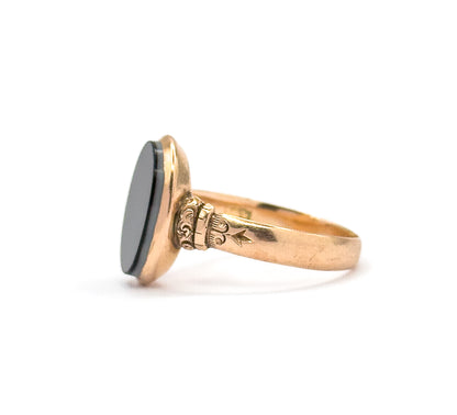 Upright on its shank against white, the dark oval agate angled toward the camera so its face and the surrounding bezel wall show together above the engraved star on the shoulder.