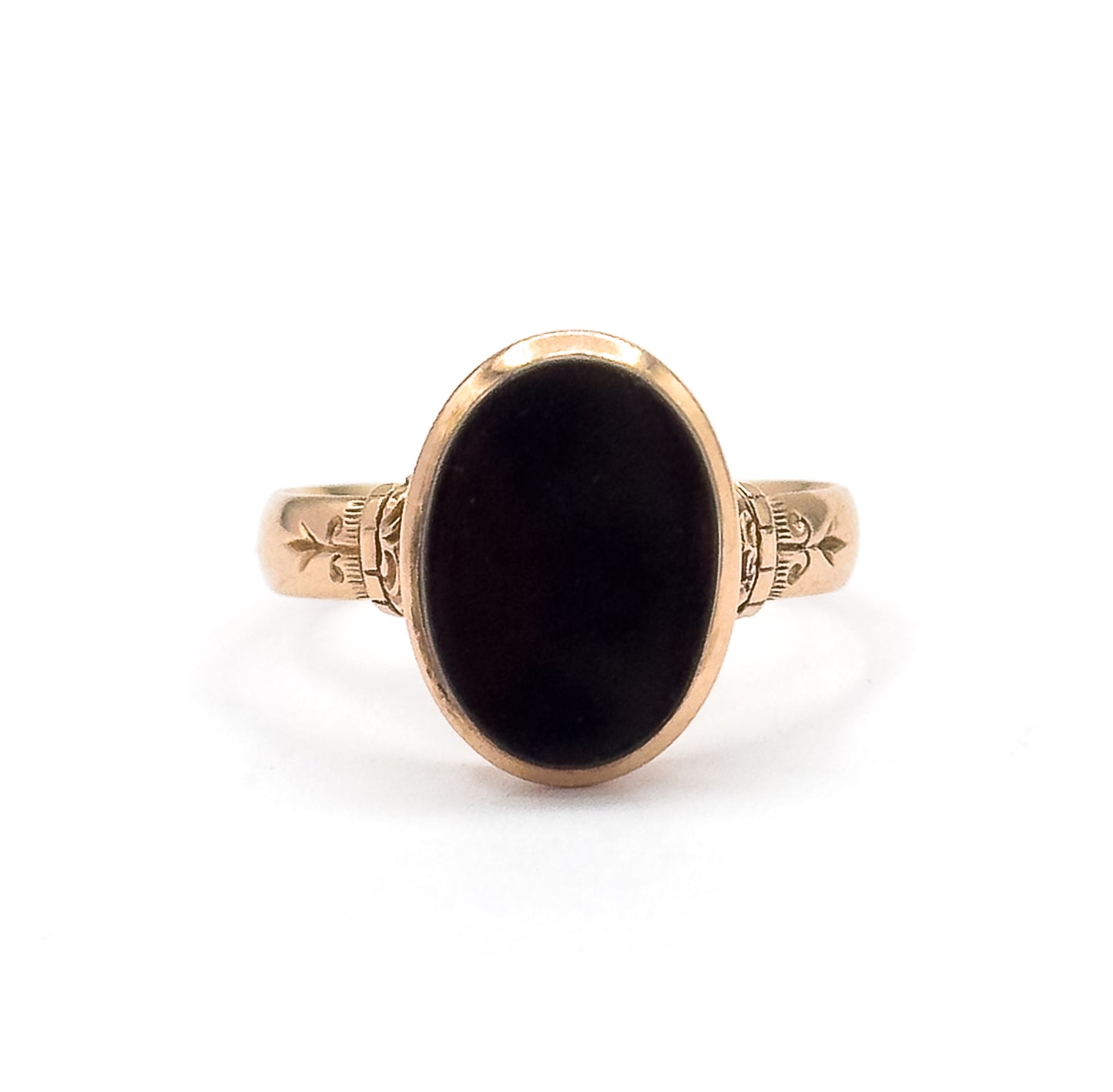 Closer crop of the face against white, the black agate oval filling its yellow gold bezel while the engraved leaf-and-scroll motifs on both shoulders read clearly beside the ridged collars.
