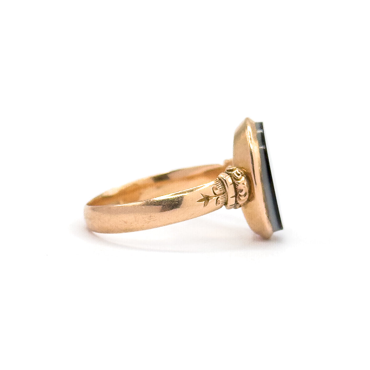 Profile from the opposite side against white, the agate's face angled away so the engraved star and scrolled shoulder stand out where the shank rises to meet the deep bezel.