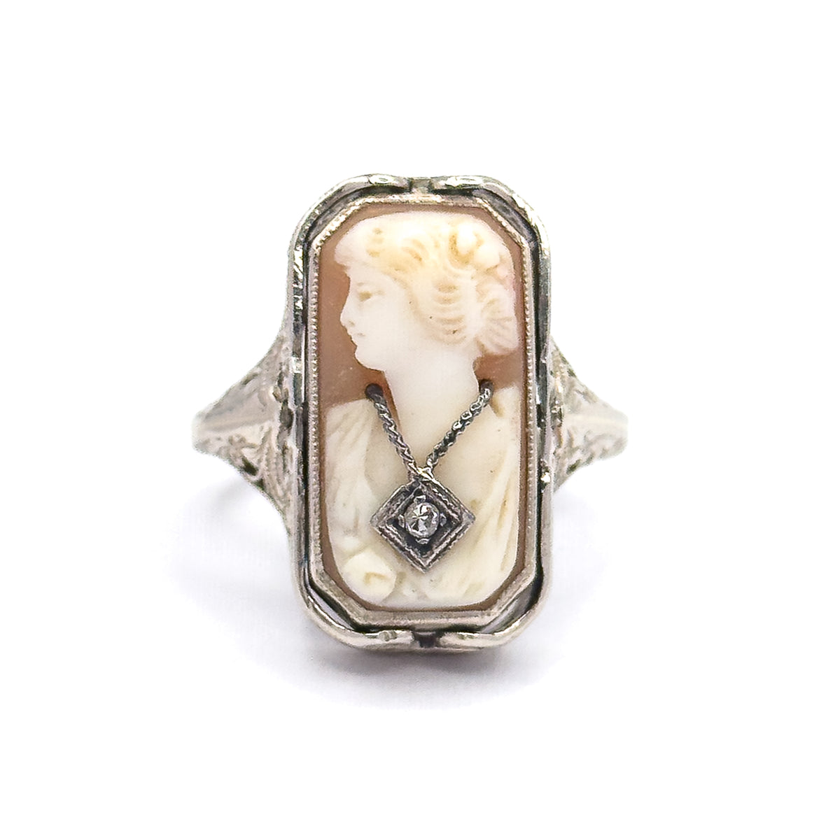Straight-on close view of the cameo face filling the frame, the carved profile and her diamond-set necklace centred within the white gold bezel, filigree shoulders just visible either side.