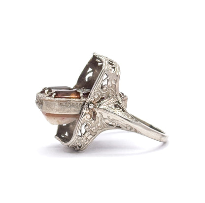 Side profile with the rectangular face tilted mid-pivot, showing the small pin in the pierced gallery wall that lets it rotate, plus the engraved shoulder and slim shank.