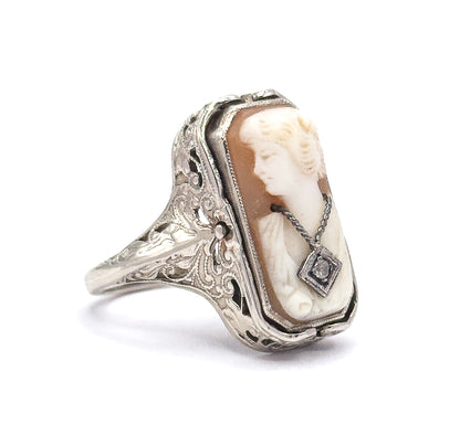Angled three-quarter view of the cameo side, the left-facing carved profile with finger-wave hair and a tiny necklace holding a diamond, framed by the pierced filigree gallery and engraved shoulders.