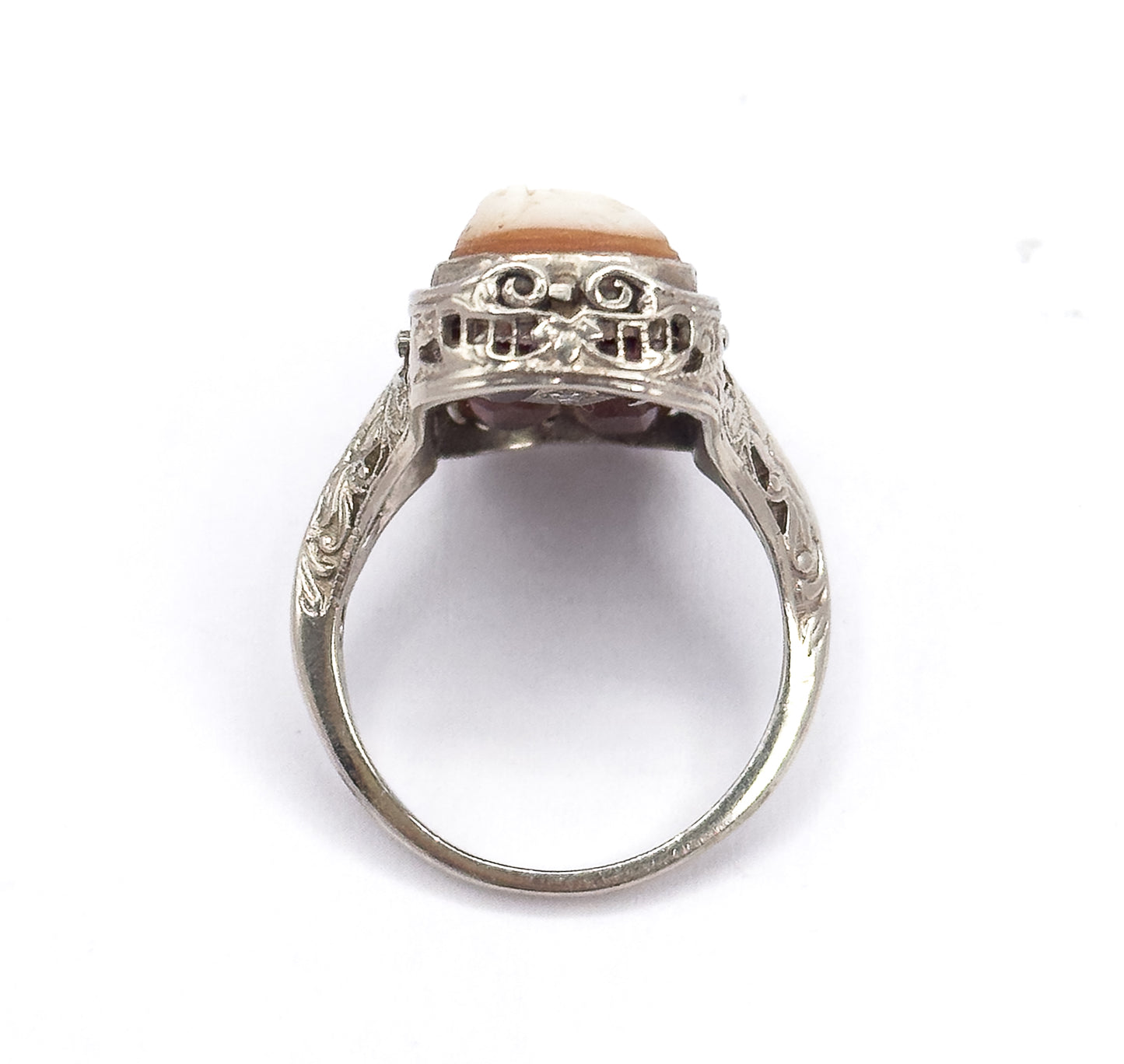 Upright end-on view looking through the open circle of the shank, showing the pierced scrollwork gallery from the side with the pale cameo edge above and engraved shoulders flanking it.