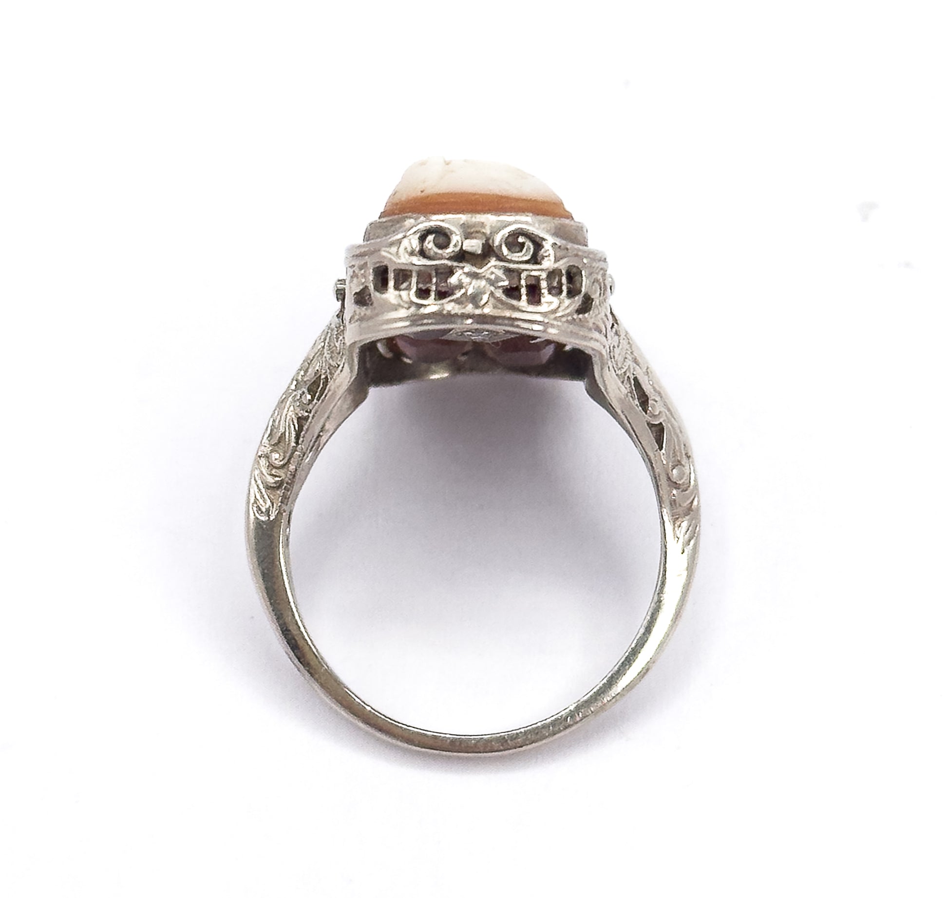 Upright end-on view looking through the open circle of the shank, showing the pierced scrollwork gallery from the side with the pale cameo edge above and engraved shoulders flanking it.