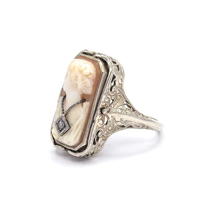 Steeply angled view from the cameo's lower corner, the tiny diamond-set necklace nearest the lens while the deep filigree side plate and its scroll piercing show the setting's height above the shank.