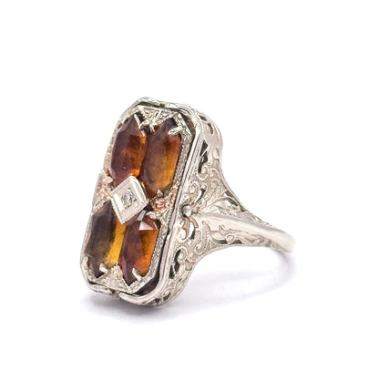 Art Deco cameo and citrine flip ring in 14K white gold, angled to show the citrine side with four prong-set orange stones around a small diamond in a filigree gallery.