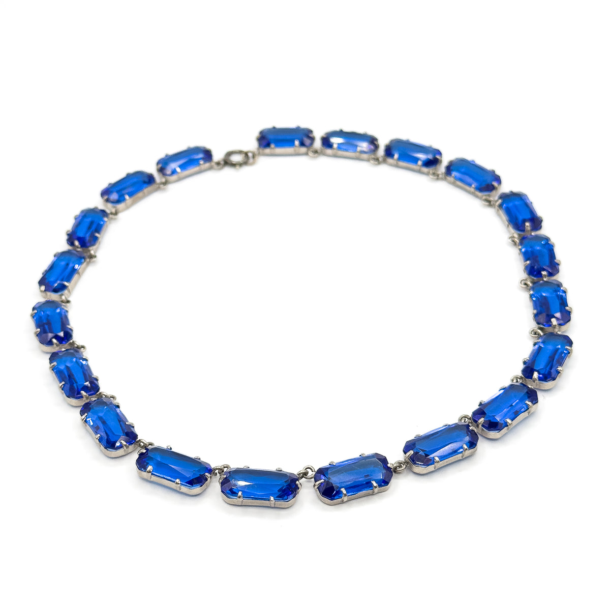 The whole collar laid flat in an open oval on white, clasp at the top and the largest cobalt blue glass links at the bottom front, showing how the row graduates around the neckline.