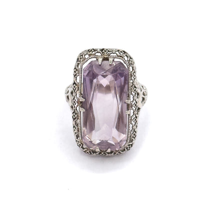 Straight down onto the face, the pastel purple amethyst fills the softly rectangular head with double prongs at each corner and milgrain-edged filigree framing it all around.