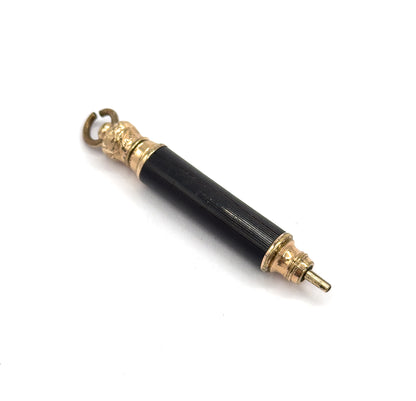 Diagonal view emphasising the lower gold tone end, where a stepped, ribbed ferrule caps the fluted black barrel and the slim tapered tip stands out from it toward the lower right.