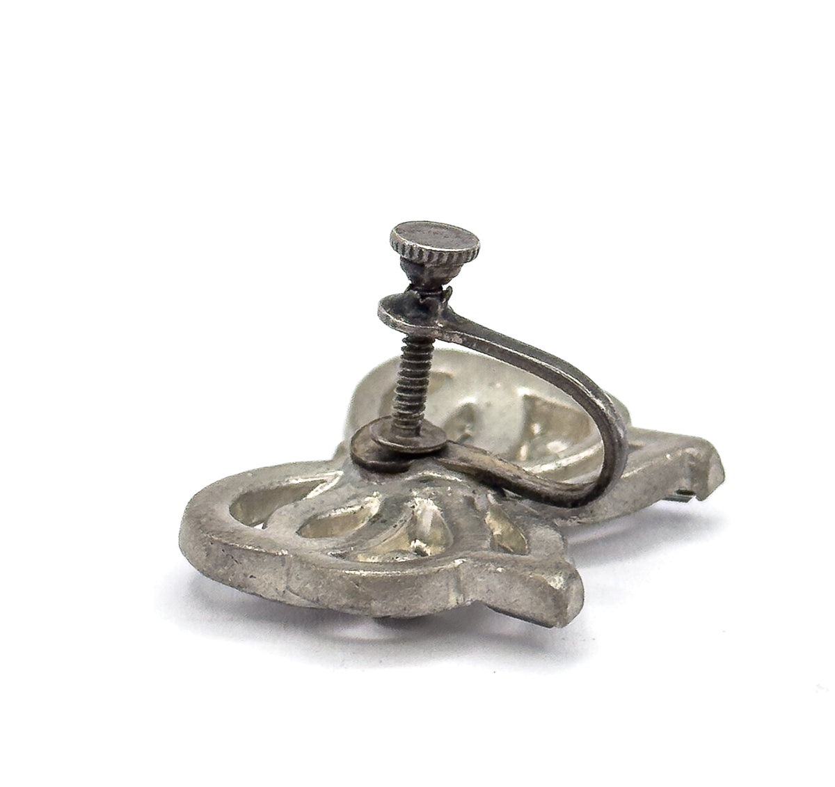 The reverse of one earring, angled to show the sterling silver screw back with its knurled screw knob, curved wire arm and the openwork backing of the bow.