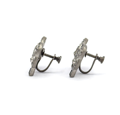 Both earrings seen edge-on in profile, showing how slim and flat the bows sit while the threaded screw posts, knurled knobs and curved wire arms extend to one side.