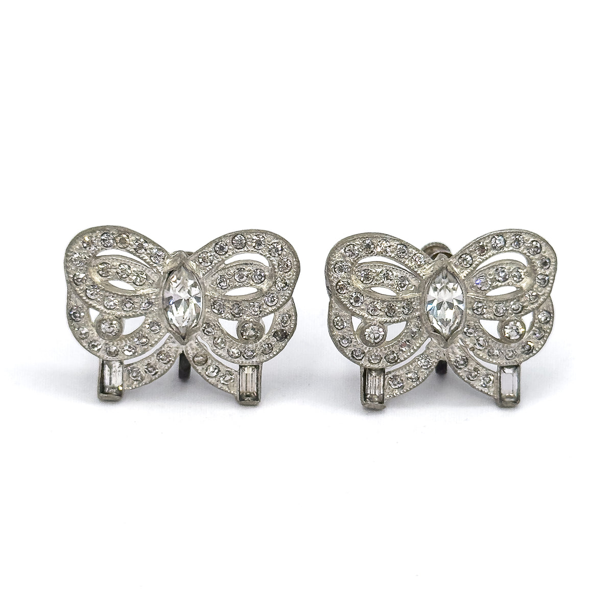 Both bows squared to the camera face-on, side by side, showing the full symmetry of each ribbon: marquise stone at the centre, round stones tracing the milgrain-edged loops, baguette at each end.