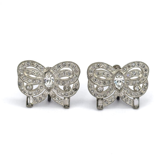 Both bows squared to the camera face-on, side by side, showing the full symmetry of each ribbon: marquise stone at the centre, round stones tracing the milgrain-edged loops, baguette at each end.