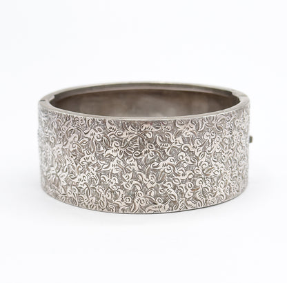 The whole wide cuff upright and closed, hand-etched ivy covering the full curved front from edge to edge while the smooth interior shows through the open top.