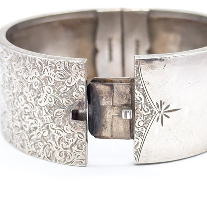 The open box clasp seen close up, the projecting tongue standing between the ivy-etched end and the plain end with its engraved star and curved border line.