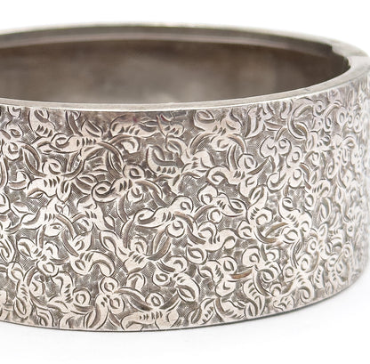 Extreme close-up of the wide band filling the frame, the dense hand-etched ivy scrolls covering the curved outer surface while the smooth interior shows past the upper rim.